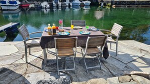 A table set for four at a waterfront location with boats in the background. - Cottage 2 meters from the sea, 2 hours from Bergen in Norway. Unike location (Vestland)