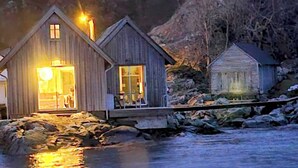 A wooden cabin with a porch, a visible interior with a chair and a table, and a small adjacent building. - Cottage 2 meters from the sea, 2 hours from Bergen in Norway. Unike location (Vestland)