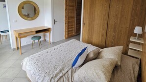 A bedroom with a bed, a desk, a chair, a wardrobe, and a mirror.