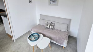 A modern bedroom with a grey sofa, a small round table, and a ceiling light.