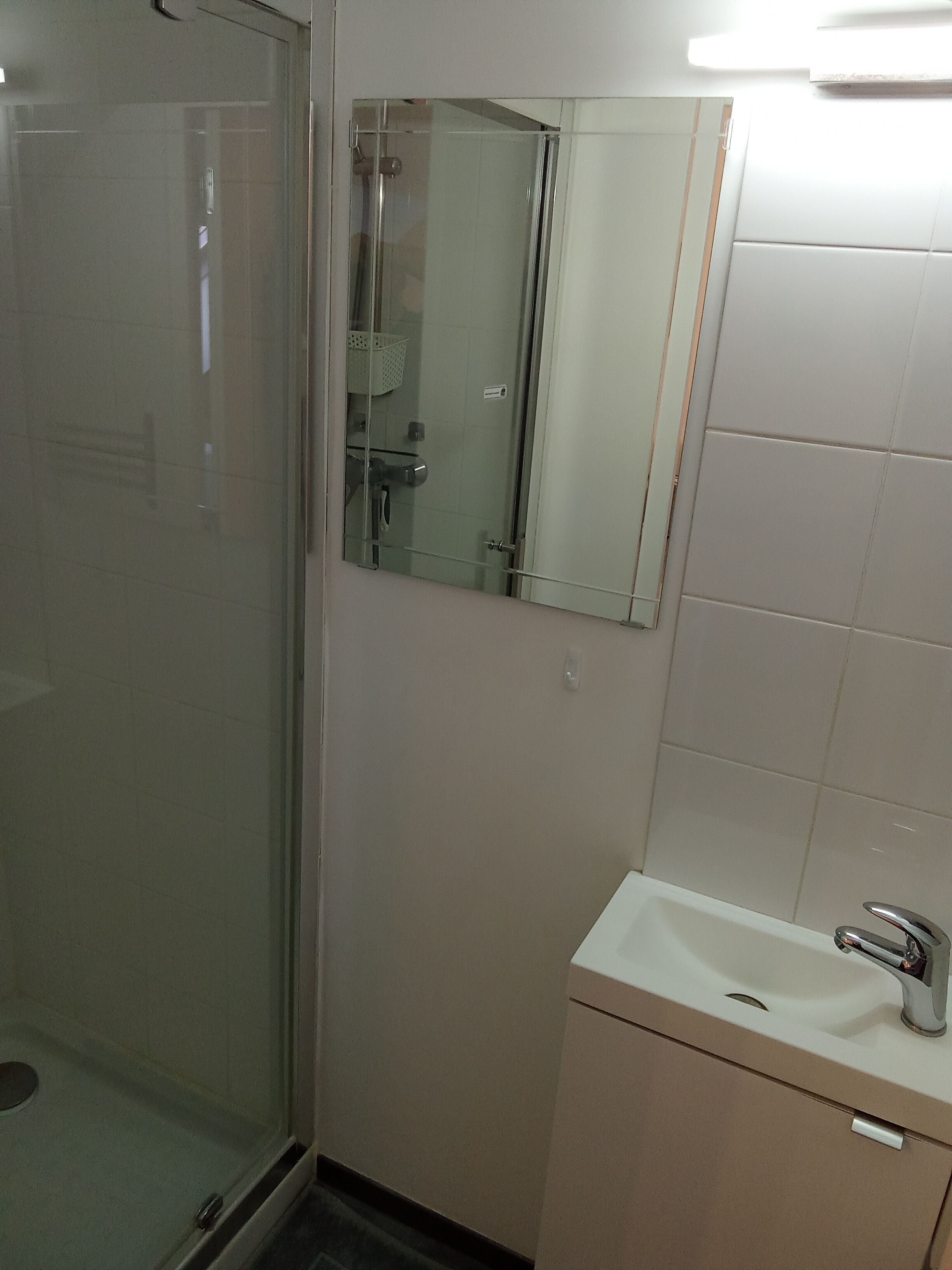 A bathroom with a glass shower enclosure, a mirror, and a sink with a faucet.
