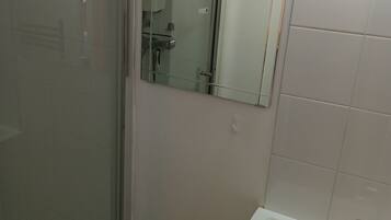 A bathroom with a glass shower enclosure, a mirror, and a sink with a faucet.