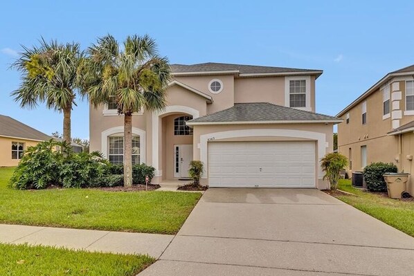 A single-story house with a garage, palm trees, and a well-maintained lawn.