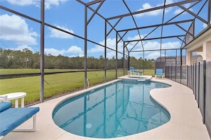 A swimming pool with a curved design, surrounded by a covered area with metal beams and glass panels.