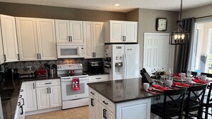 Una cocina moderna con armarios blancos, una isla central y un comedor listo para una comida.