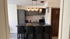 Een moderne keuken met een centraal eiland, zwarte barkrukken en hangende lampen.