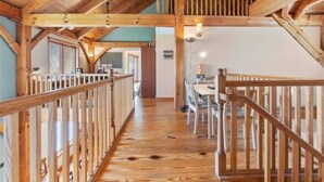 A wooden interior with a central staircase, a dining area, and a view of the outside. - Lakefront Cabin Boat slip Wifi Fishing Firepit (Orange)