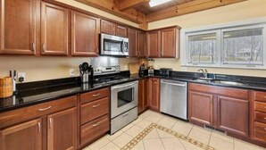 A kitchen with wooden cabinets, a microwave, stove, and dishwasher. - Lakefront Cabin Boat slip Wifi Fishing Firepit (Orange)