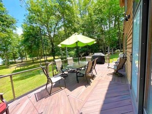 Relax on the covered deck surrounded by a serene lawn and trees.
