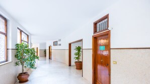 Un couloir agrémenté de plantes en pot, de portes en bois et de murs carrelés.
