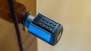 Un appareil électronique bleu et noir, vraisemblablement une télécommande, fixé à une surface en bois.