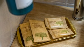 Un plateau contenant plusieurs sachets en papier, chacun portant une étiquette indiquant différents types de shampooing pour la douche, et ce, dans plusieurs langues.
