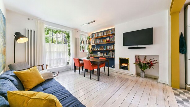 A modern living room with a sofa, a dining area, a fireplace, and a bookshelf. - Designer apartment in modern neighborhood - 15 minutes from central London (London)