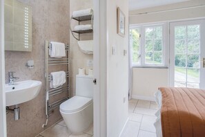 Ein Badezimmer mit Waschbecken, Toilette, Handtuchhalter und einem Fenster mit Blick auf Grünfläche.