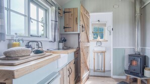 Een landelijke keuken met houten kastjes, een groot raam, een fornuis en een spoelbak.