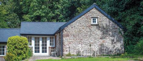 A stone building with a sloped roof, a small window, and a door.