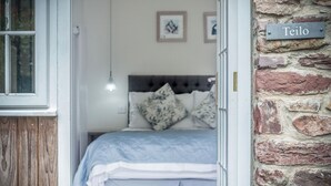 Ein Schlafzimmer mit einem Bett, einer Holztür, einer Ziegelwand und einem Schild mit der Aufschrift 'Teilo'.