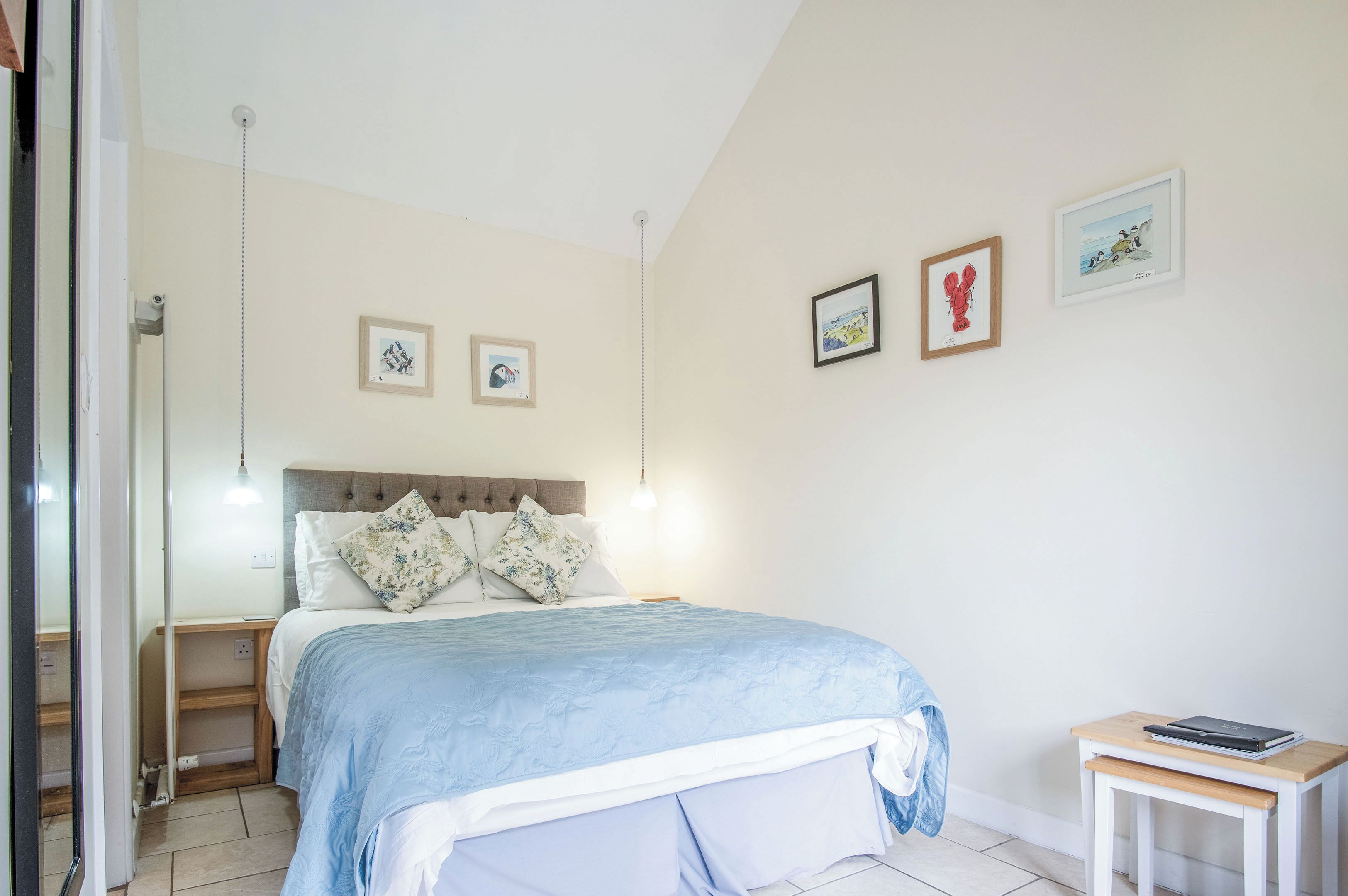 Une chambre à coucher avec un lit, des tables de chevet et des tableaux accrochés au mur.