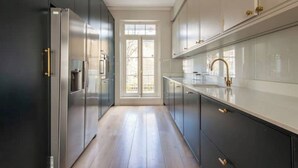 Een moderne keuken met donkere kastjes, roestvrijstalen apparatuur en een groot raam.
