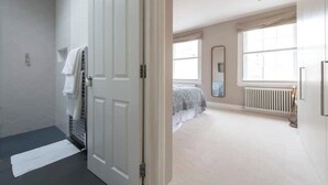 Een slaapkamer met een bed, een radiator, een raam en een deur.