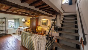 A cozy interior with a staircase, a dining area, and a living room with a sofa and a table. - La Colombaia romantic apartment (Margine Coperta-traversagna)