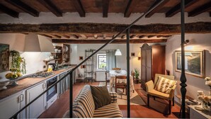 A spacious living area with a high ceiling, a kitchen with a rustic aesthetic, and a dining area with a table and chairs. - La Colombaia romantic apartment (Margine Coperta-traversagna)