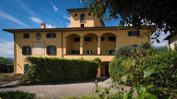 A yellow building with a central courtyard, surrounded by greenery and flowers. - La Colombaia romantic apartment (Margine Coperta-traversagna)