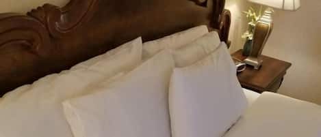 Una cama bien hecha con ropa de cama blanca y cabecera de madera.