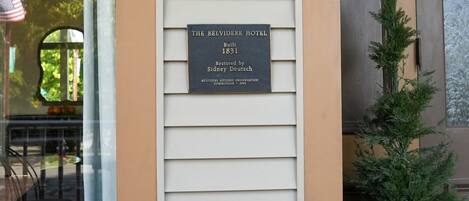 A building with a plaque indicating it is The Belvidere Hotel, built in 1831 and restored by Sidney Deutsch.
