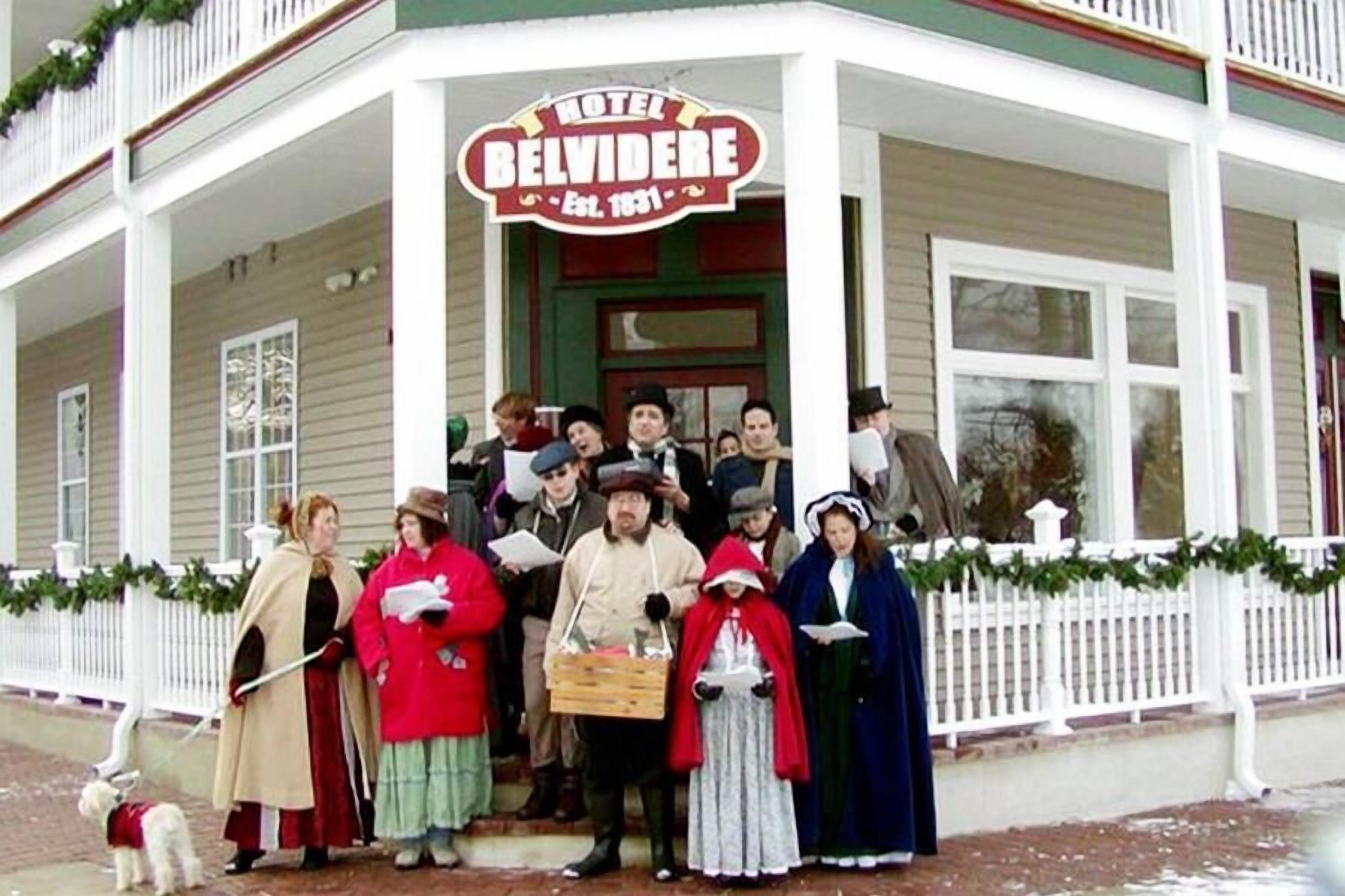 A group of people in historical costumes standing in front of a building with a sign that reads "Hotel Belvidere."