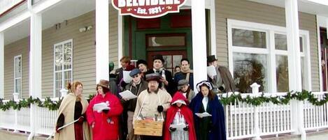 Un grupo de personas vestidas con trajes de época posan frente a un edificio con un letrero que dice 'Hotel Belvidere'.