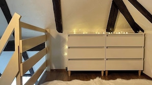 A room with a white dresser, a white furry rug, and a wooden railing. - Just take a break, Sauerland, Alme Brilon (Brilon)