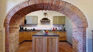 A kitchen with a brick archway, wooden cabinets, and a central island. - Vivaia Arceno Rentals Club, Villa in Chianti , Exclusive Pool Concierge Freewifi (San Gusmè)