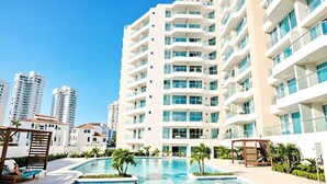 A modern hotel with a large swimming pool, multiple balconies, and a clear blue sky. - Apartamentos Aragoa - Cerca al Mar by SOHO (Santa Marta)