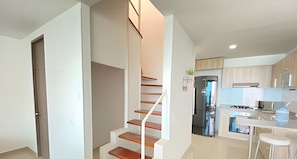 A modern kitchen with a built-in oven, a refrigerator, and a dining area with a white table and two chairs. - Apartamentos Aragoa - Cerca al Mar by SOHO (Santa Marta)