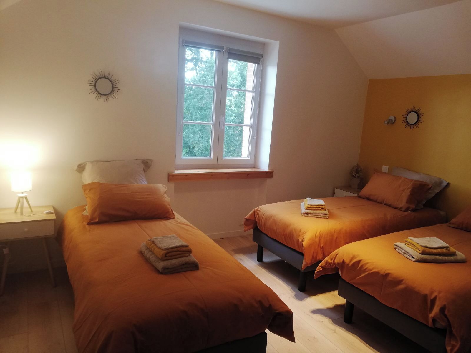 A bedroom with two beds, a window, a nightstand, and a wall clock.