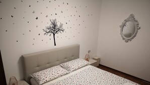A neatly made bed with floral bedding, a bedside lamp, and a green towel on the side.