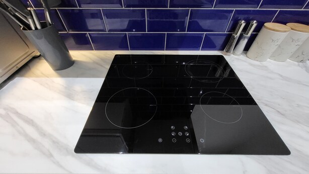 A kitchen with a black induction cooktop, a marble countertop, and a blue-tiled backsplash. - Best Priced Apartment In Danum  19 (Doncaster)