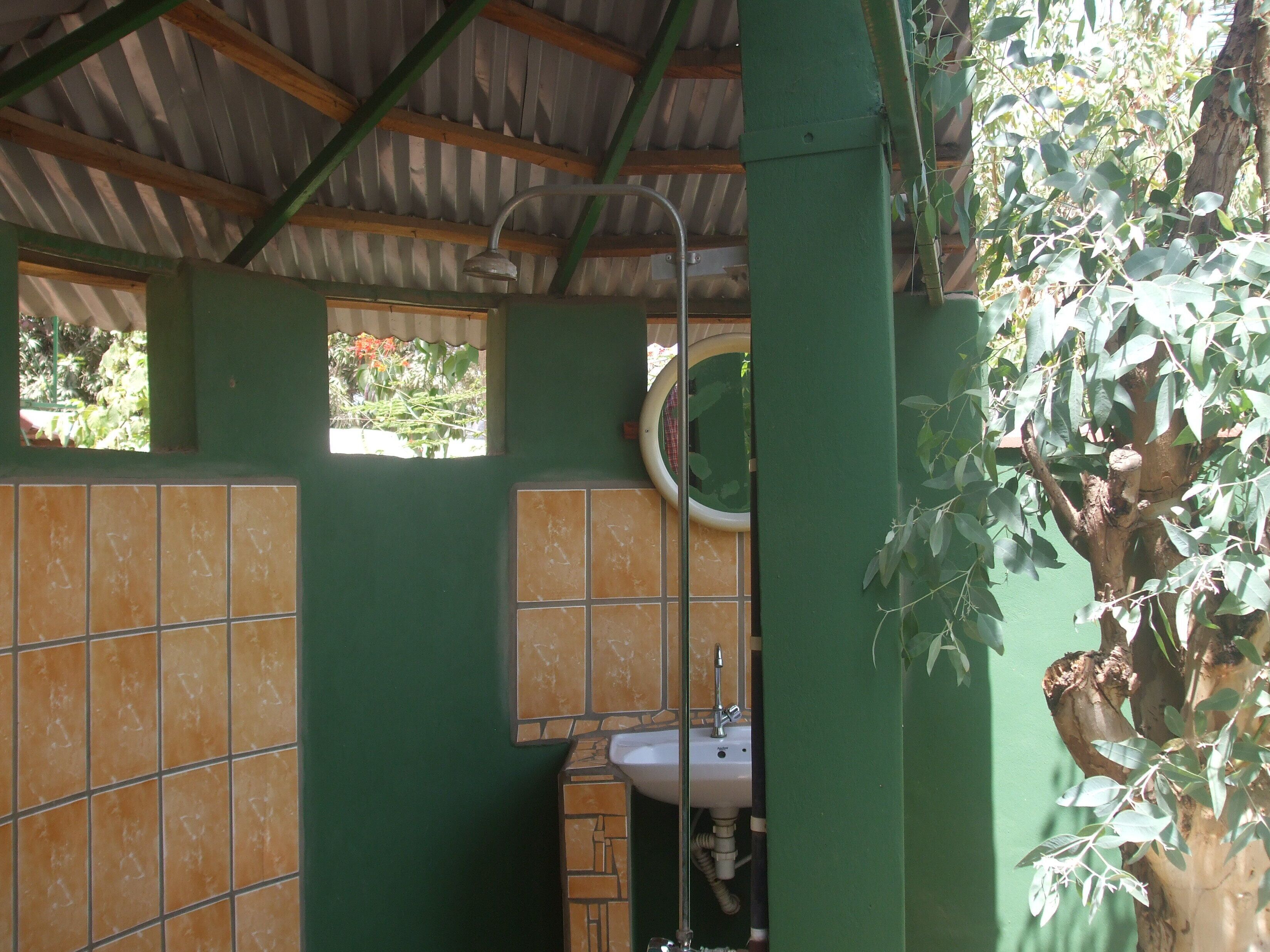 A bathroom with green walls, a tiled floor, a sink, and a shower.
