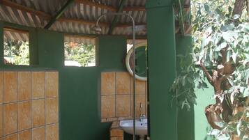 A bathroom with green walls, a tiled floor, a sink, and a shower.