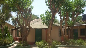 A building with a tiled roof, surrounded by trees and plants. - Camping-Sukuta & Lodge (Serrekunda)