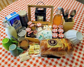 A table with various food items and condiments, including jars of preserves, a bottle of honey, and a loaf of bread. - Le Relais de Louis (Orbigny)