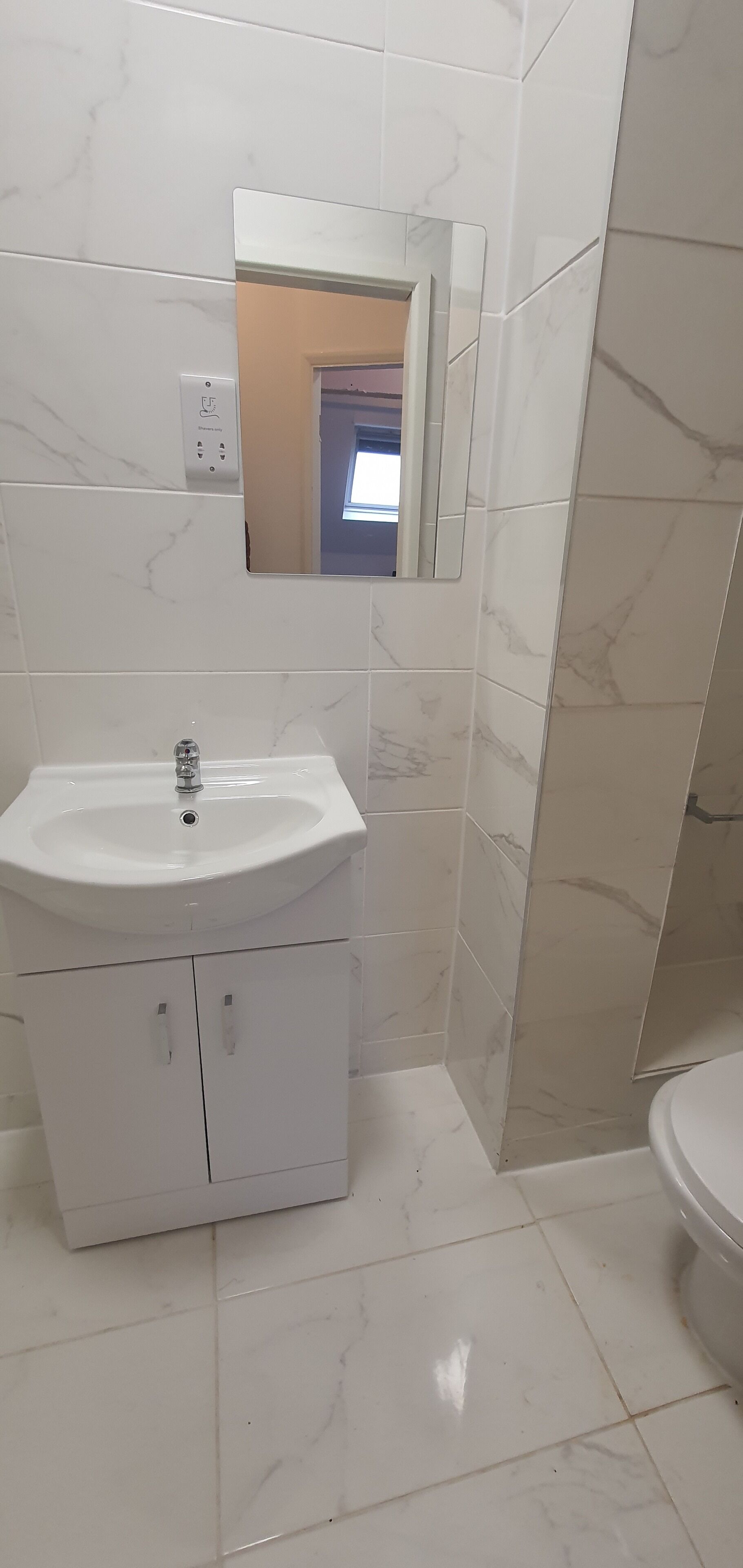 Une salle de bain avec un lavabo blanc, un miroir et des toilettes.