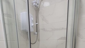 Een douchecabine met glazen wanden, een handdouche en een bedieningspaneel.