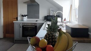 Une cuisine moderne avec un îlot central, un four à micro-ondes, une cuisinière et une horloge au mur.