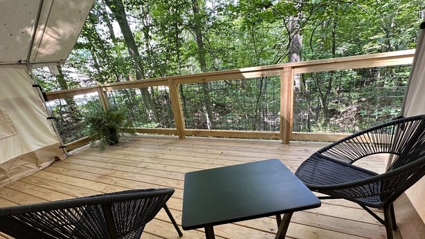A covered outdoor area with a wooden deck, two wicker chairs, and a table.