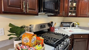 A kitchen with wooden cabinets, a stainless steel stove, a microwave, and a sink.