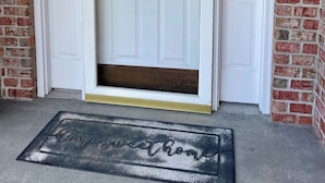 A white double door with a glass panel, a brick wall, and a doormat with "Home sweet home" written on it.
