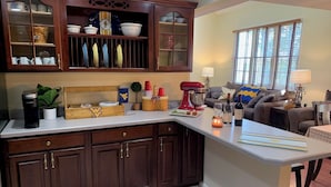 A kitchen with dark wood cabinets, a white countertop, and a dining area with a table and chairs.