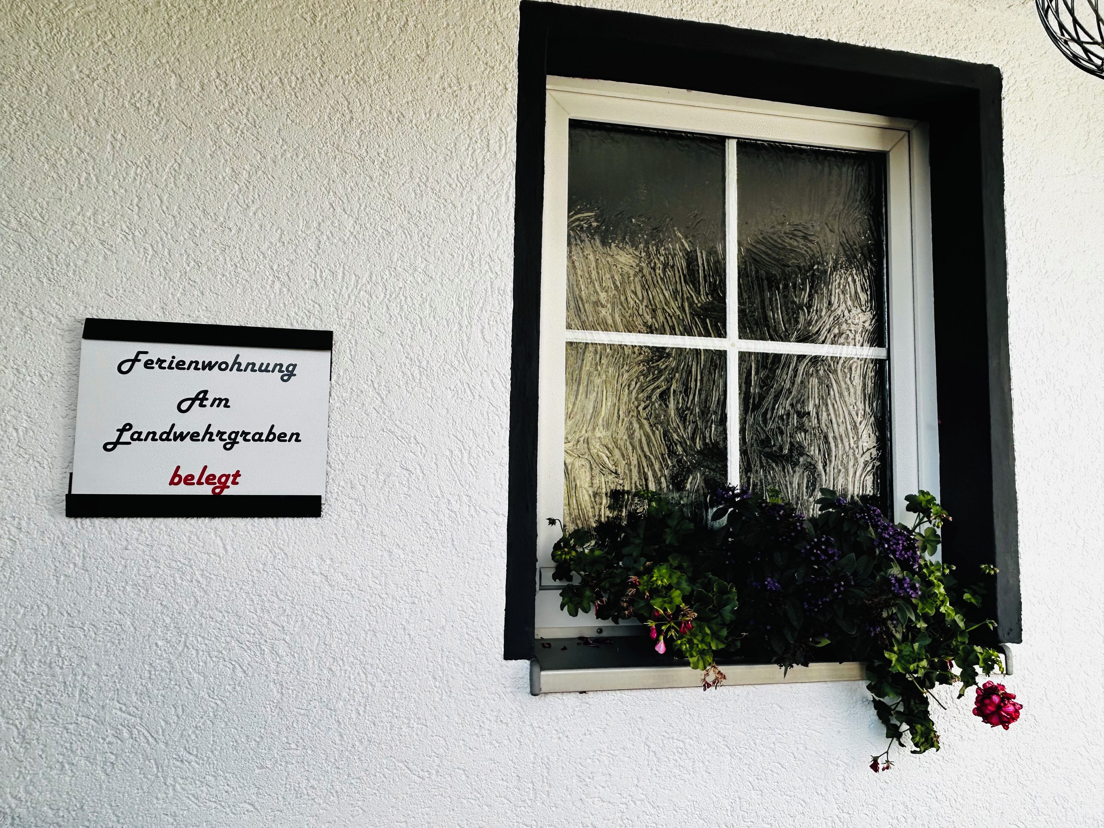 A window with a white frame and a sign on the wall to the left.